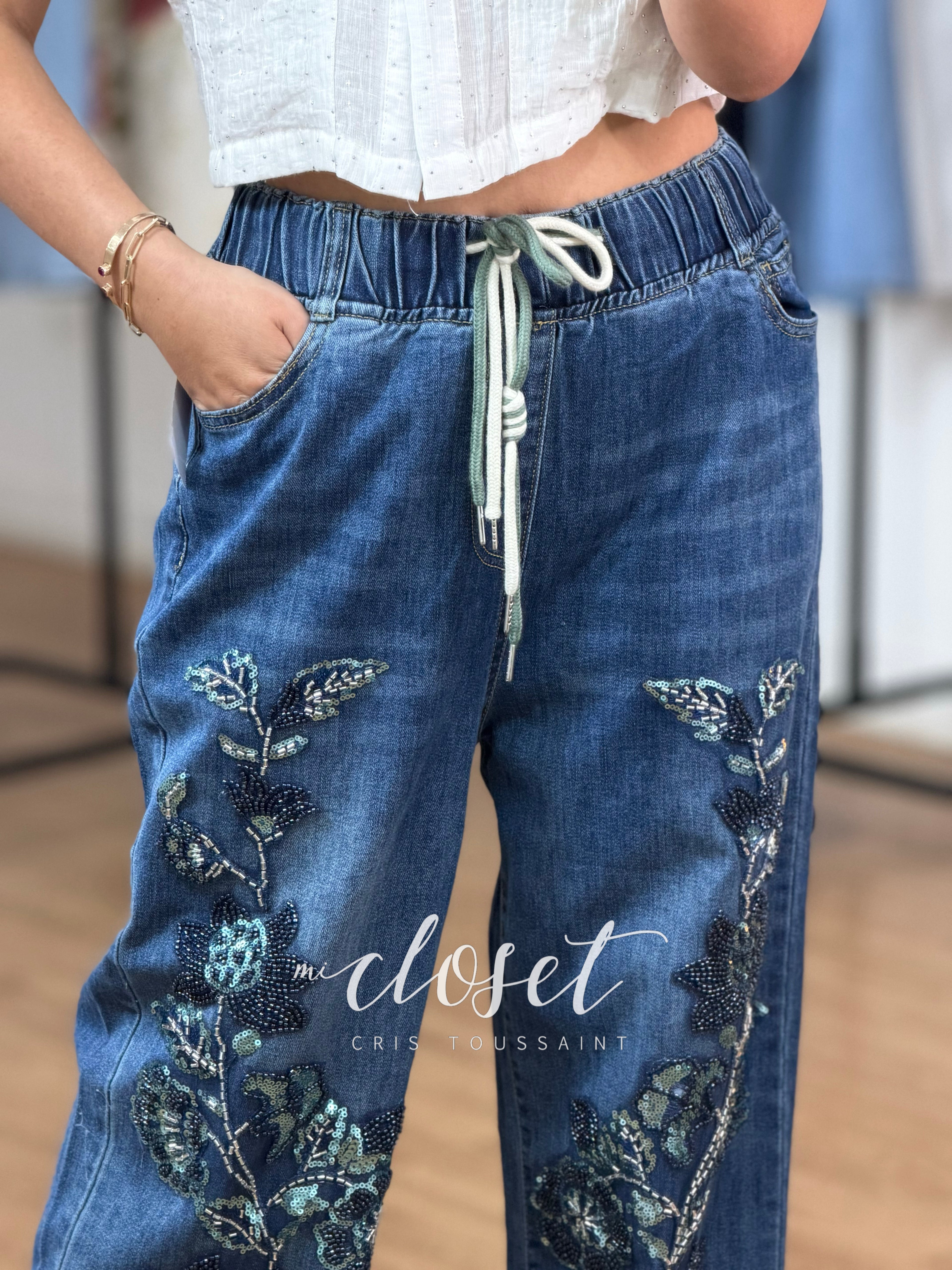 JEANS CON RESORTE COMPLETO Y CORDONES AJUSTABLES EN CINTURA; APLICACIONES DE LENTEJUELA Y CHAQUIRA EN PARTE DE ENFRENTE